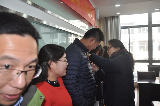老教师为新教师佩戴校徽